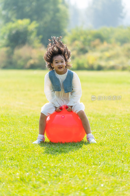 一个小女孩在草地上玩球