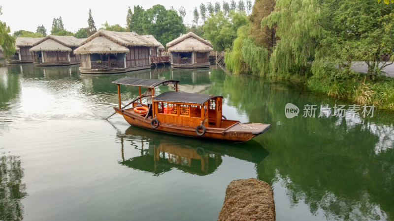 水上木船与岸边茅草屋风景