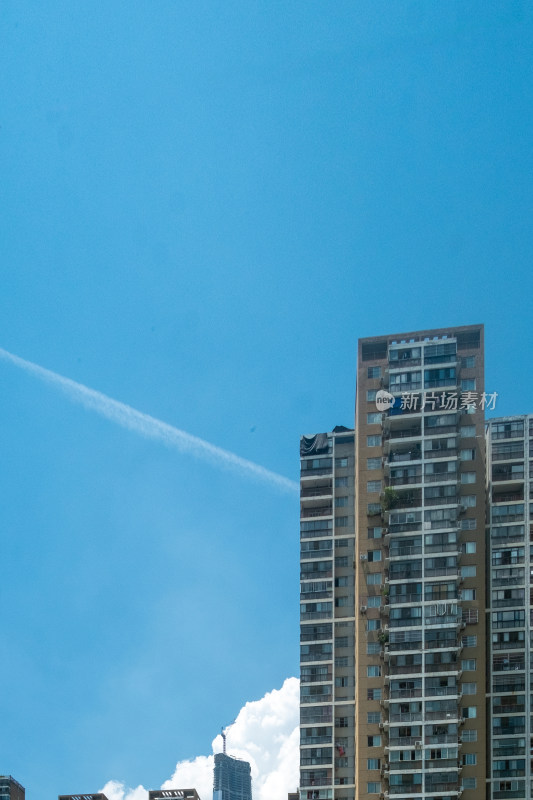 蓝天下带尾迹云的高层居民楼景象