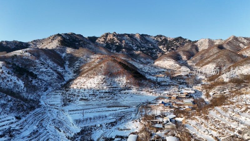 山村雪景下的梯田与房屋景象