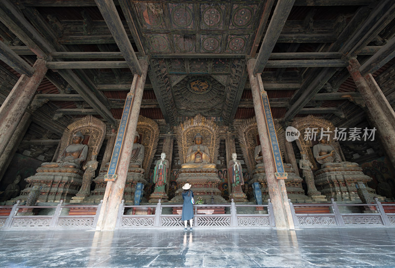 大同善化寺古建筑内多尊佛像前站着一位女士