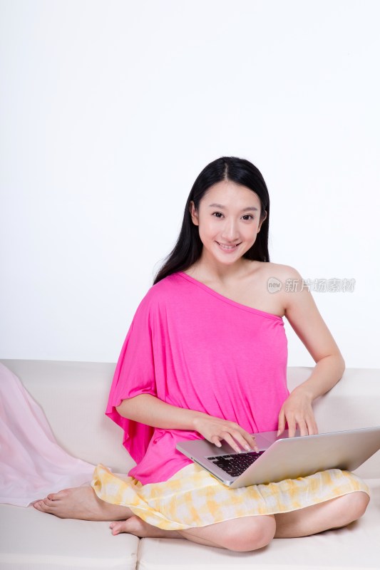 棚拍年轻女人坐在沙发上使用笔记本电脑上网购物