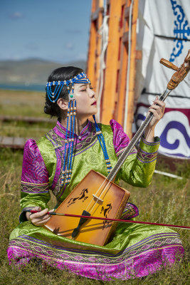 蒙古包前穿蒙古族服饰拉马头琴的蒙族女乐手