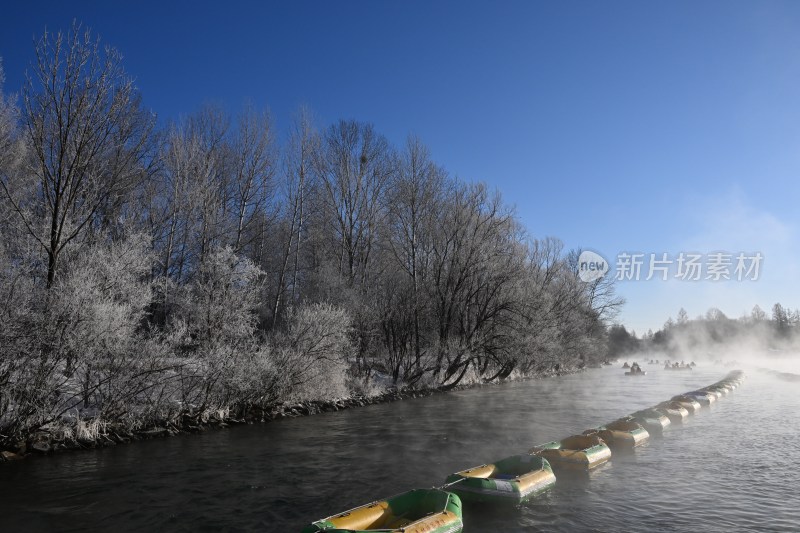 河岸树林覆雪 水面漂流艇成排