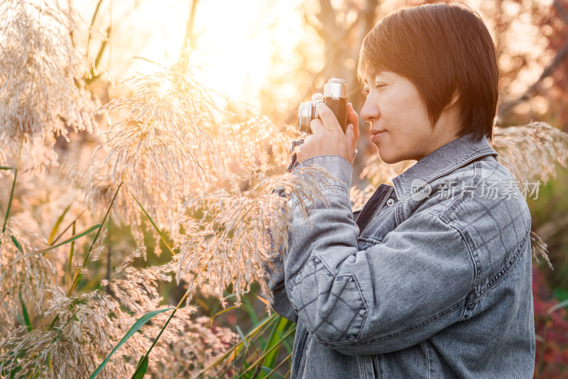 秋天在公园用照相机拍照的中国女性形象