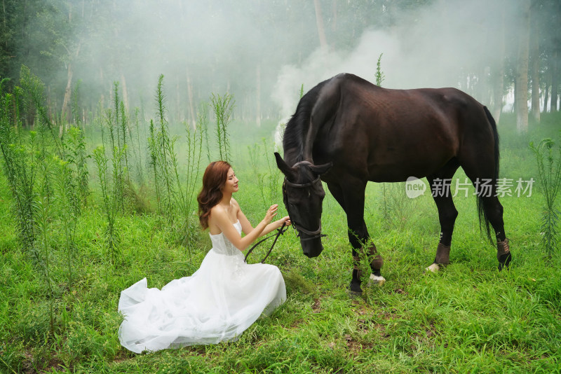 草地上穿婚纱的青年女人和马