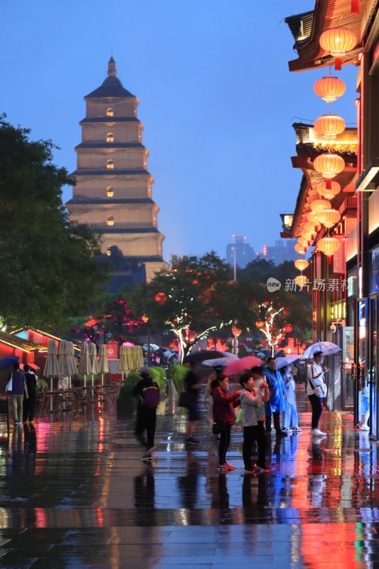 大雁塔下行人打伞的雨夜街景