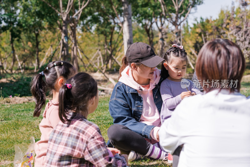 秋天午后围坐在草坪上玩耍的母亲和女孩