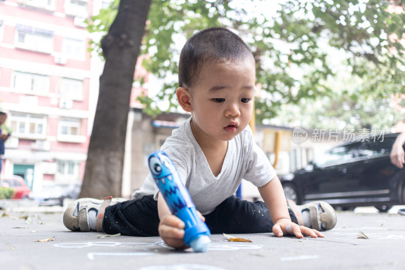 一个小男孩坐在地上用粉笔写字