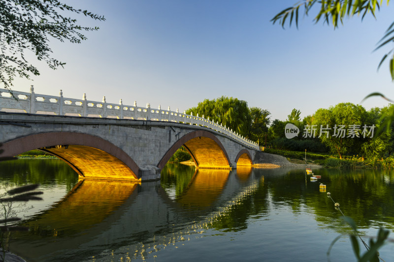 水上石桥倒映美景，周边绿树环绕