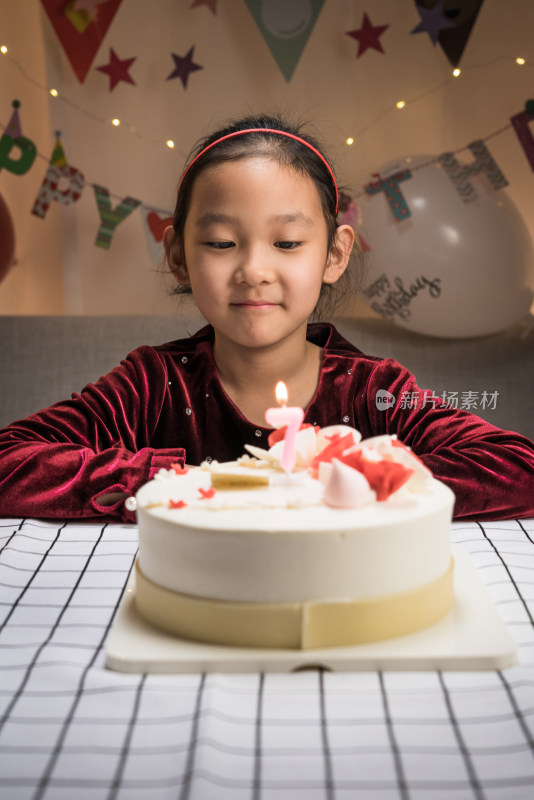 中国女孩对着生日蛋糕许愿吹蜡烛