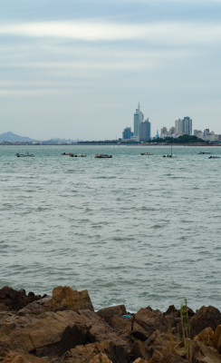 从礁石上远望海那边的城市