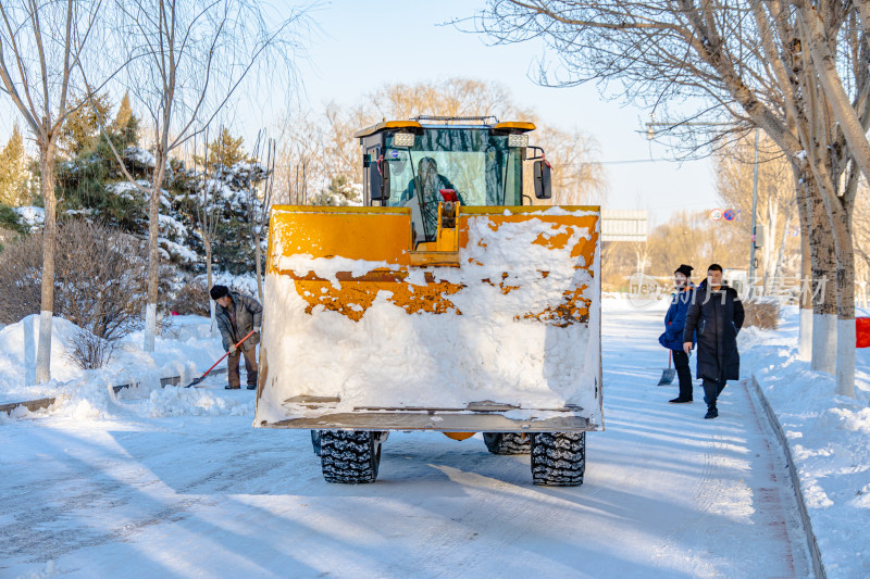 黄色装载机在积雪道路上作业