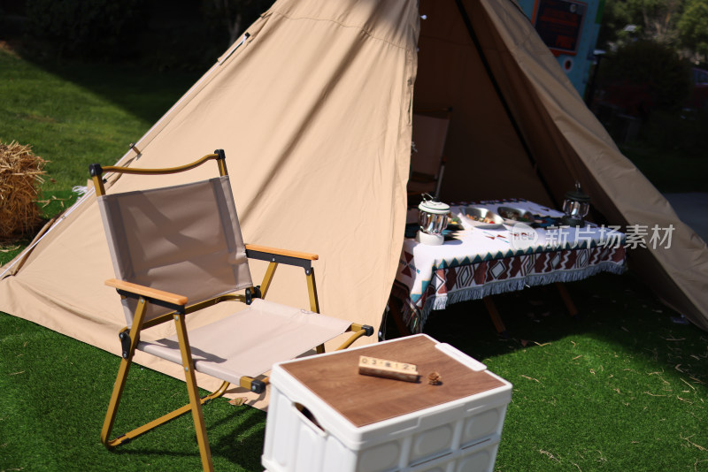 草地上的露营帐篷和空椅子和桌子