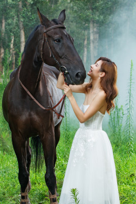 户外穿裙子的漂亮年轻女人和马