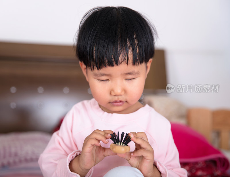 认真摆弄梳子的小女孩