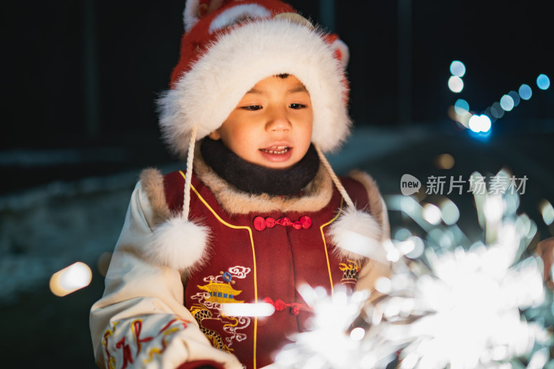 中国农历春节穿传统服饰的小男孩夜晚放烟花