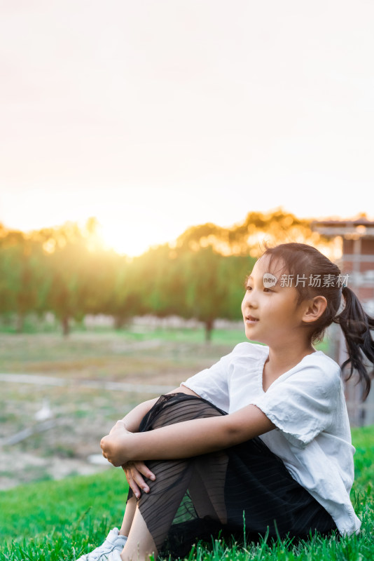 傍晚坐在草坪上欣赏夕阳的中国女孩