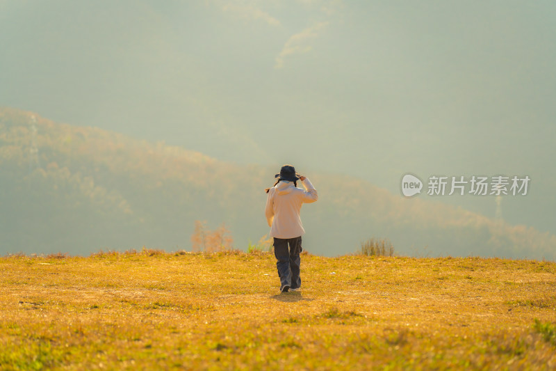 背靠天空站在草地上的人的后视图