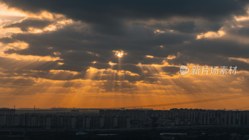 城市上空云层间隙透出阳光的景象