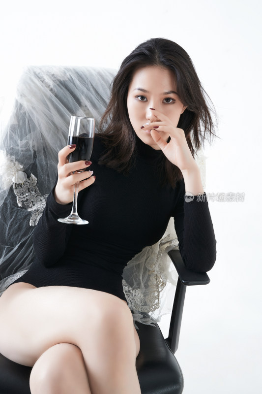 坐在椅子上独自品尝红酒的亚洲女性