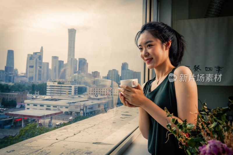 年轻女人站着窗边往外看