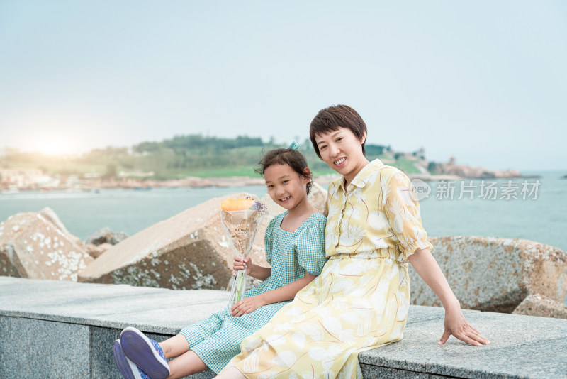 夏天坐在海边玩耍的中国母女