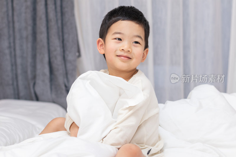 一个小男孩坐在舒适的床上开心笑