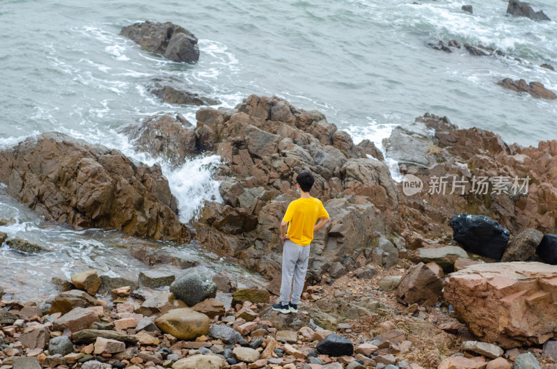 青岛海边海岛上一个穿黄色衬衫的男子