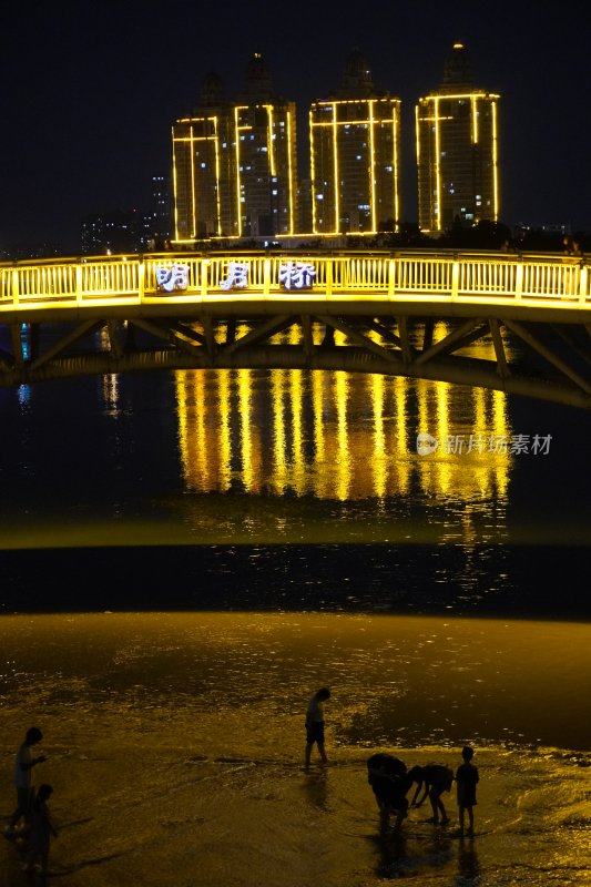 明月桥夜景下沙滩嬉戏人群