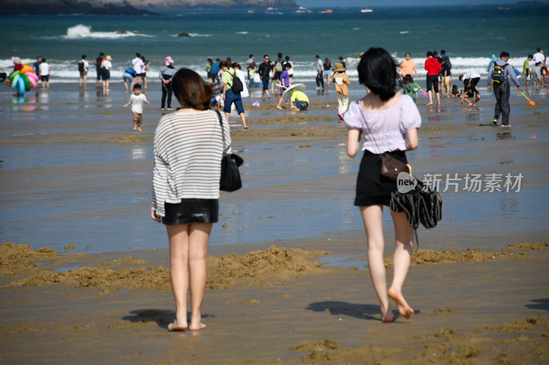 两位女子在热闹海滩漫步