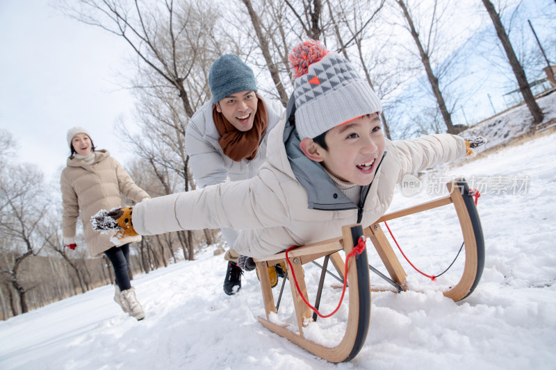 在雪地上玩雪橇的一家人