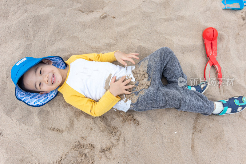 快乐的小男在海边玩沙子