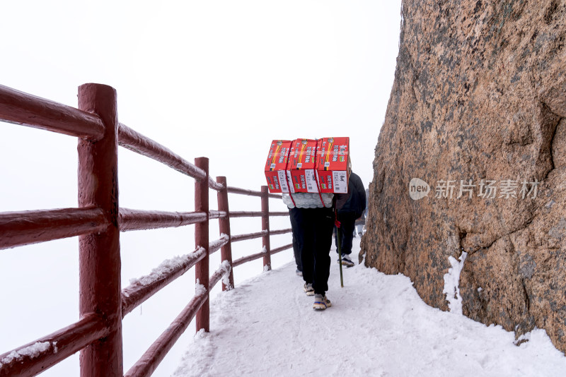 寒冷冬天景区栈道上背送泡面物资的民工