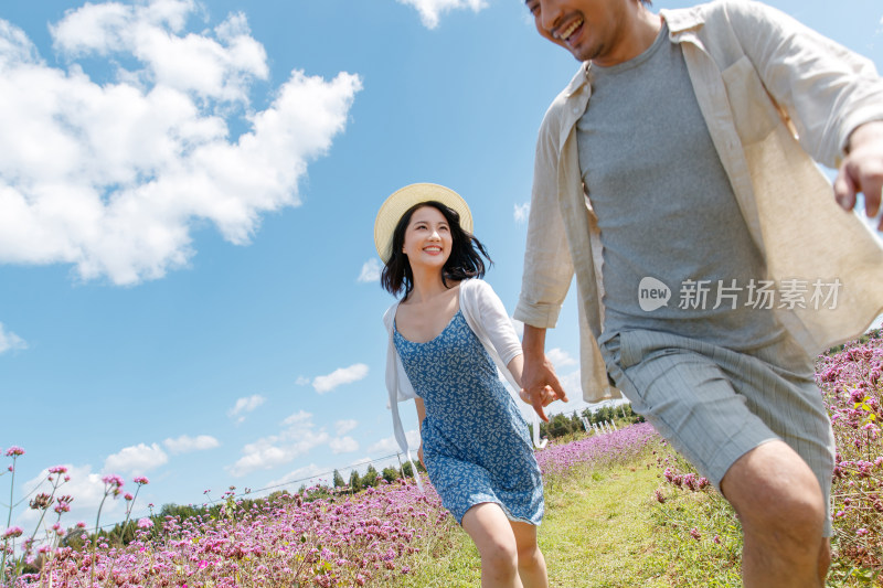 青年夫妇手牵手在花海里奔跑