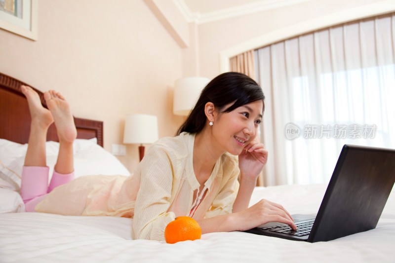 年轻女人趴在床上看电脑