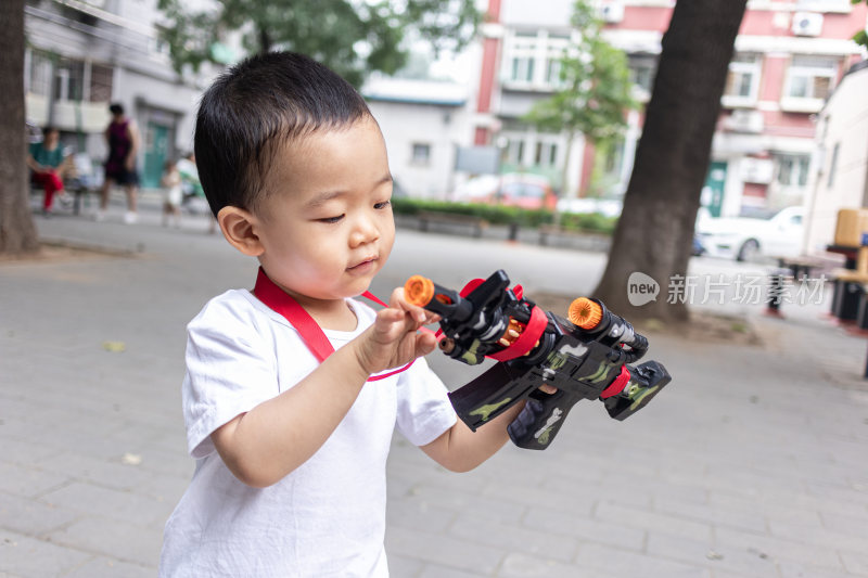 一个小男孩在院子里玩玩具枪