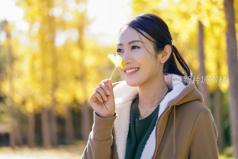 快乐的年轻女子手拿银杏叶