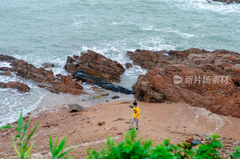 青岛海边海岛上一个穿黄色衬衫的男子