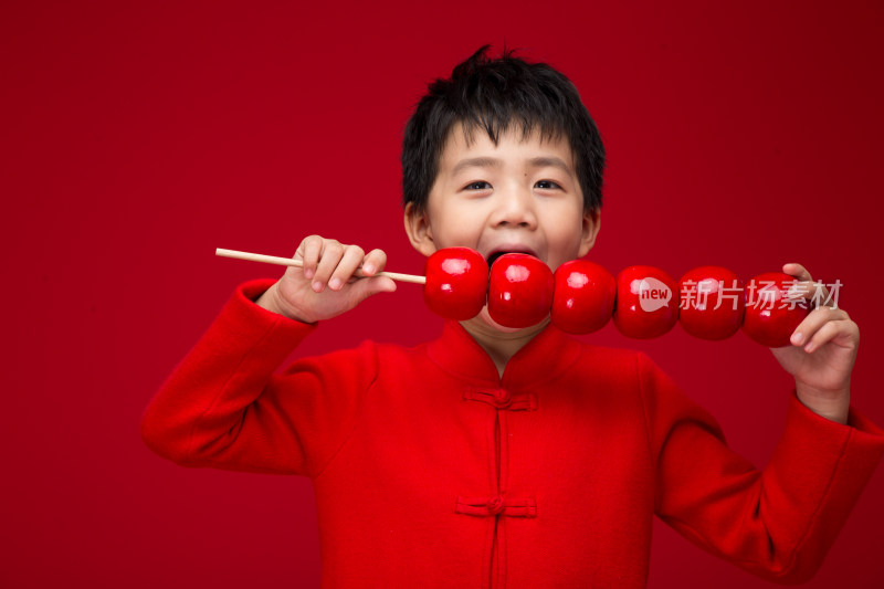 红色背景下拿着棒棒糖的中国小男孩