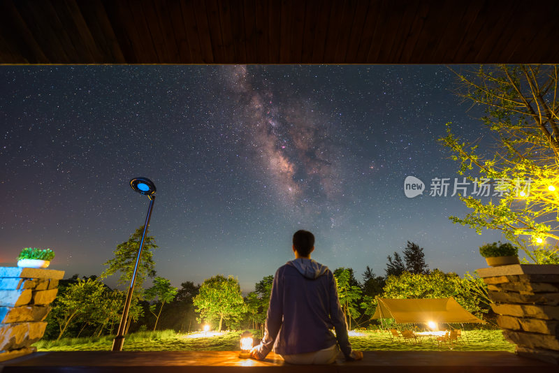 一个男人坐在屋檐下仰望星空