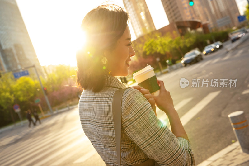 青年女人拿着饮料走在马路上