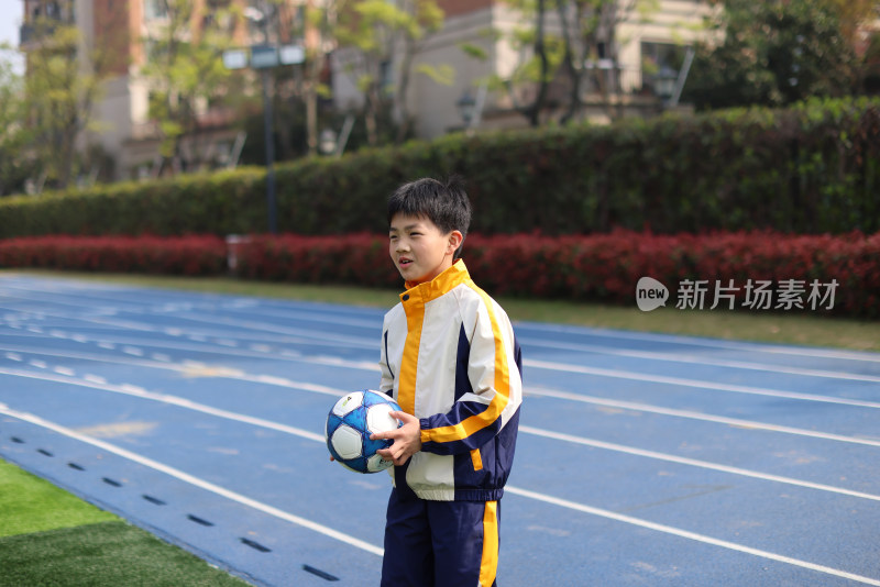 男孩在足球场上拿着足球的肖像