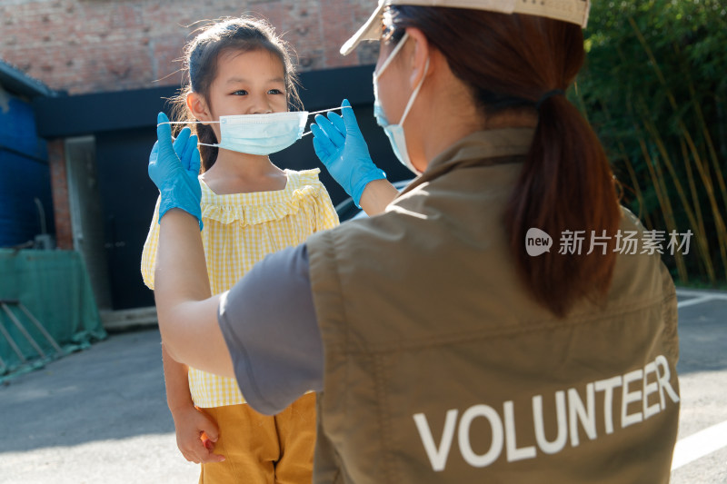社区志愿者帮小女孩戴口罩