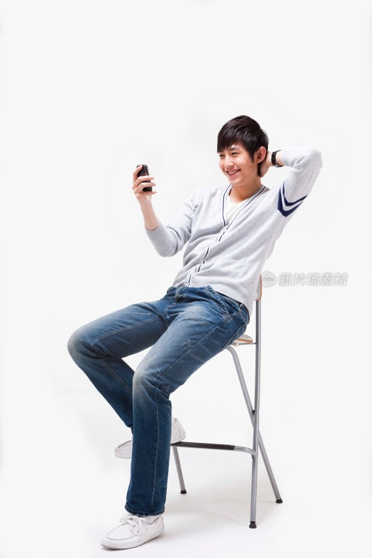 年轻男人做在椅子上使用手机