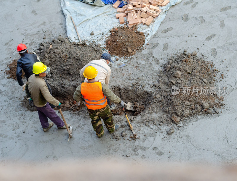 建筑工地上几个合作挖坑的建筑工人