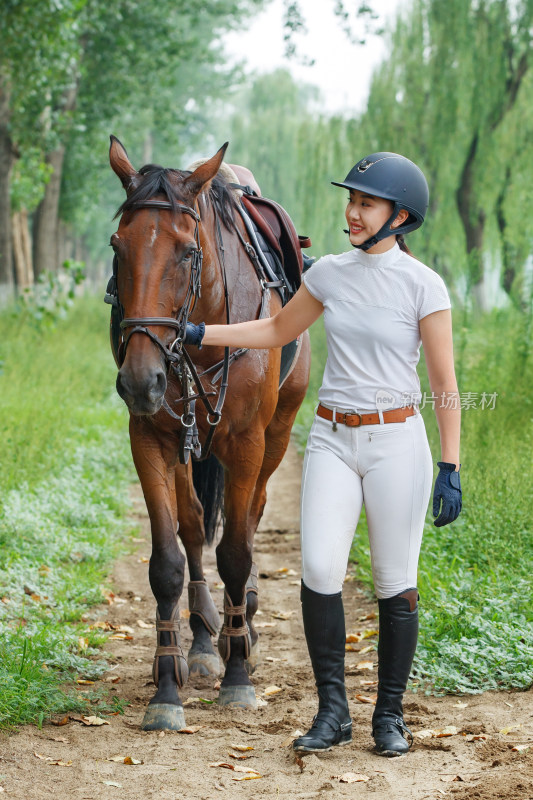 林间小路牵着马匹步行的漂亮年轻女孩