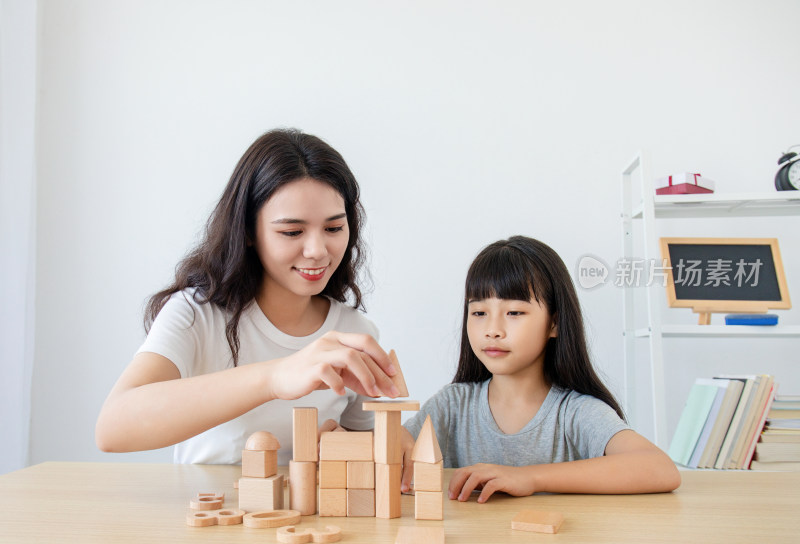 一位中国妈妈陪伴女儿玩积木