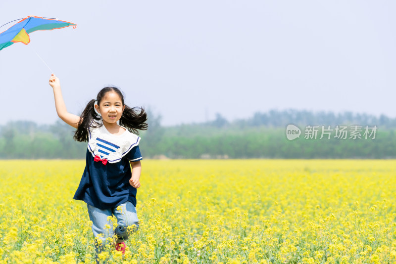 夏天拿着风车在油菜花田中奔跑的女孩