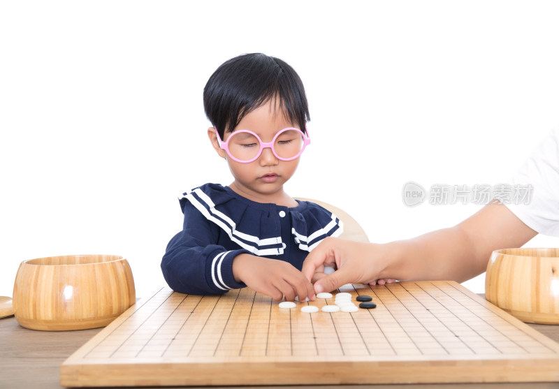 戴眼镜框的小女孩在老师的指导下学习下围棋